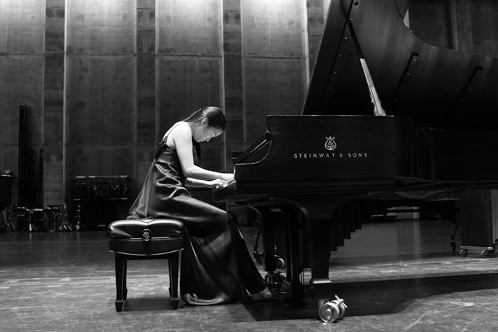 Soojin Jin playing a Steinway grand piano on a concert stage, seen in profile
